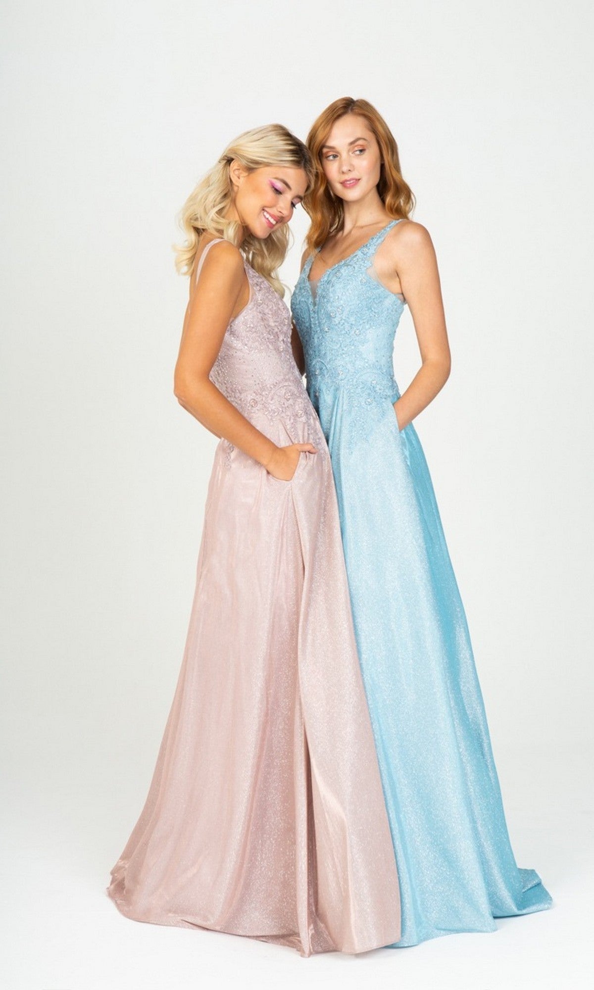 Two women stand side by side in floor-length Eureka 9606 prom dresses—one with an embroidered bodice and the other with an elegant a-line skirt—in light pink and light blue, set against a plain white background.